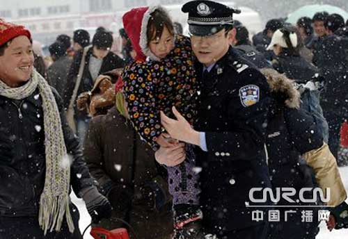 民警在风雪中为一名旅客抱小孩,帮助他们排忧解难