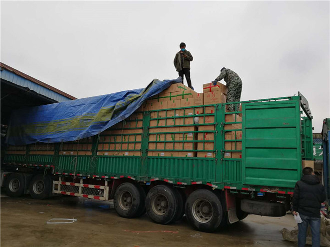 几名工人正把装好红椒的一盒盒纸箱往一辆13米长的半挂货车上搬运