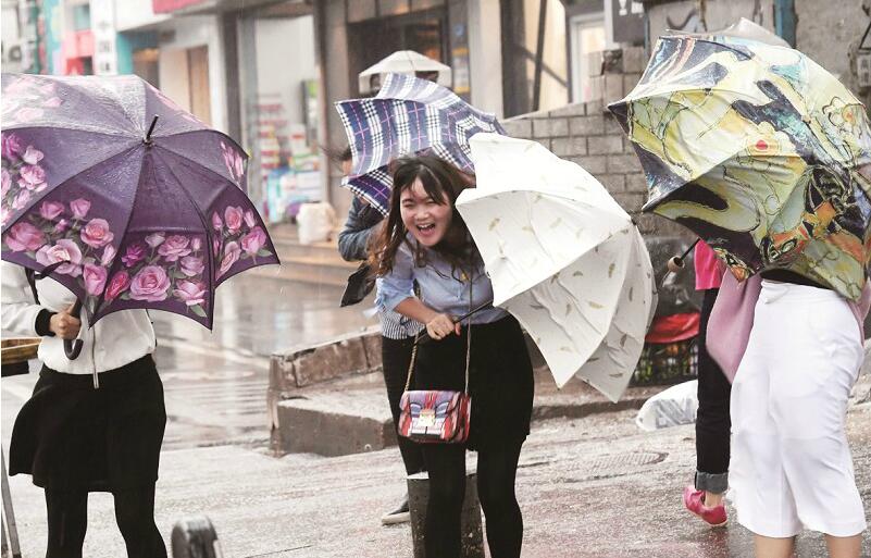 昨日,大风把行人的雨伞吹得变形了.楚天都市报记者李辉摄